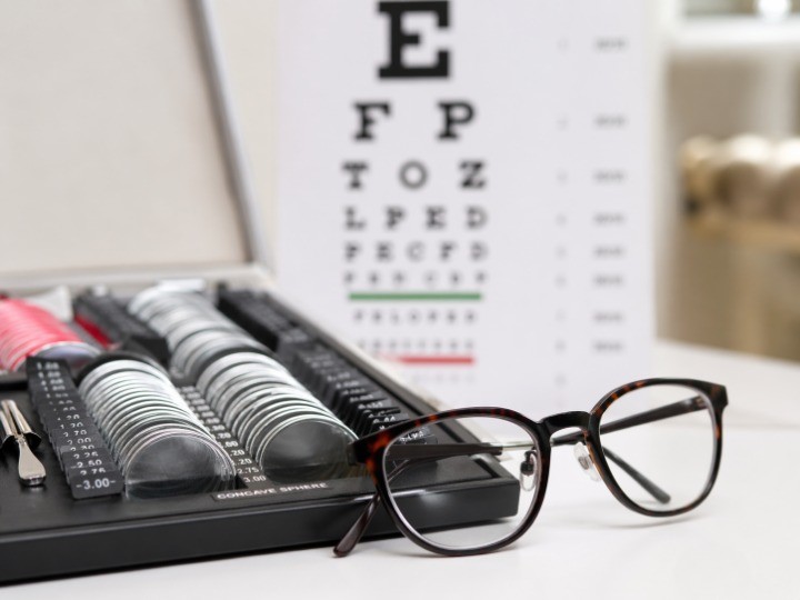 ophthalmic lens samples on optical workbench with eyeglass frame and inspection light